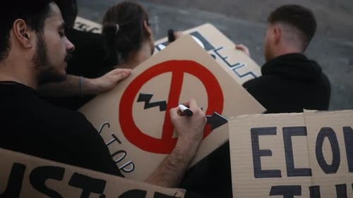 Des militants multiraciaux conçoivent des panneaux de protestation contre les banques, la crise financière et l'inflation mondiale