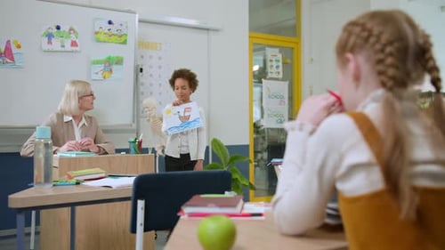 Elementary School Class Children Communicate with the Teacher Answering Question