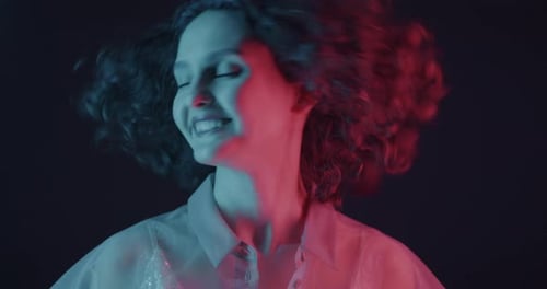 Woman with Curly Hair Smiling in Red and Blue Light