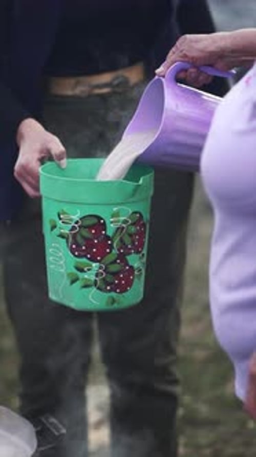 Boiling milk is poured from one can to another can to be distributed to the poor