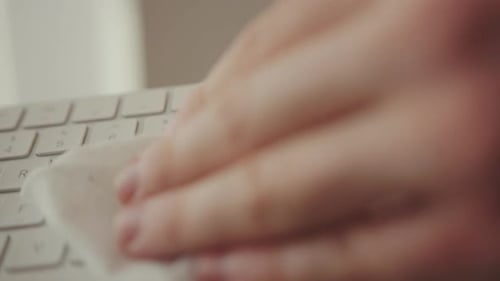 Close up of Hand Cleaning White Wireless Keyboard