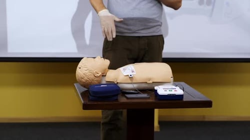 Instructor Demonstrating Defibrillator Training with Medical Dummy