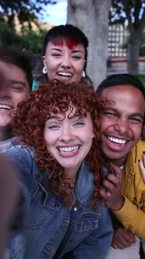 Young multicultural students capturing group selfie with joyful expressions, bonding outdoors in sce