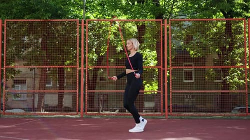 Young Woman Skipping Rope on Basketball Court