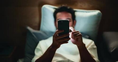 Man Using Smartphone Lying in Bed at Night
