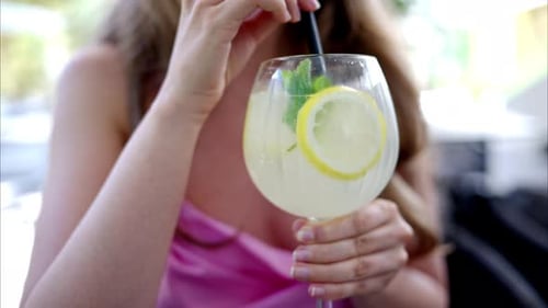 Woman Stirs Refreshing Cocktail with Lemon and Mint