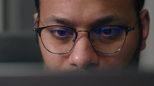 Close Up Concentrated Focused Male Eyes in Eyeglasses Looking at Laptop Monitor Screen Light