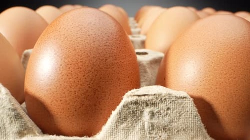 Macro video showcasing fresh eggs nestled in a delicate paper tray.