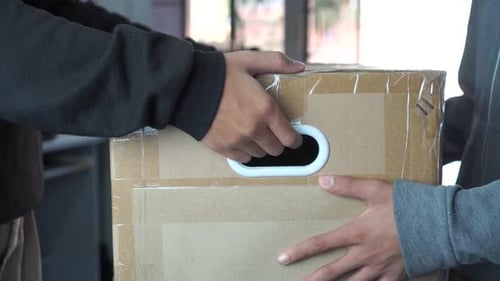 Package Delivery: Hands Exchanging a Sealed Cardboard Box