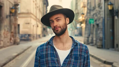 Stylish Caucasian Male Tourists in Hat Looking to Camera and Smiling Standing at Old City Street