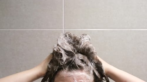 Woman Washing Hair with Shampoo in Shower
