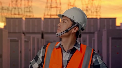 Close Up Of Asian Male Engineer Looking Around With Arms Akimbo with High Voltage Power