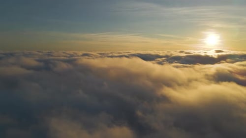 Aerial View of Bright Yellow Sunset Over White Dense Clouds with Blue Sky Overhead