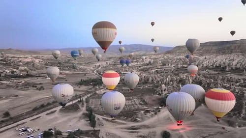 Hot Air Balloons Float Over Desert Landscape at Sunrise