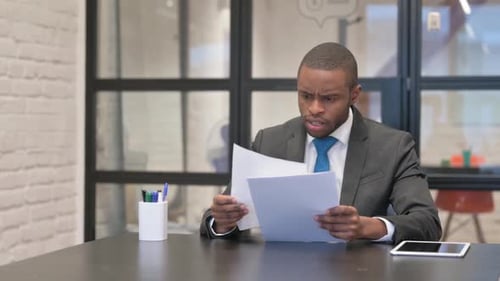 Young adult throwing documents at desk in frustration