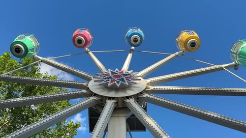 Ferris wheel spinning on sunny day. Low angle view