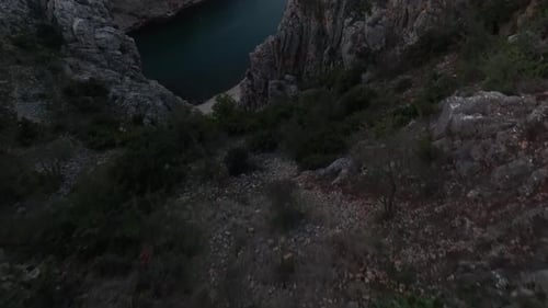 Aerial video of a man standing on rocks looking at the river in the canyon