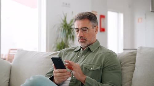 Man Using Smartphone Relaxing at Home on Couch