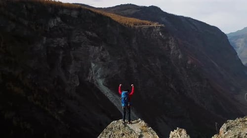 Hiker Celebrating Reaching Mountain Peak with Arms Raised