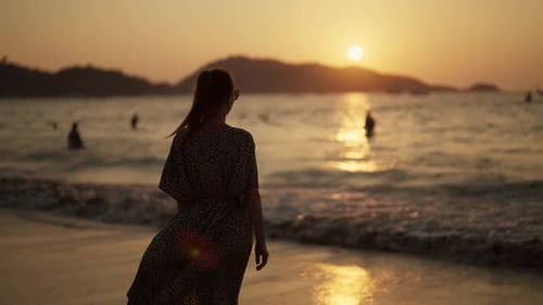 Charmante Frau genießt Sonnenuntergang am Strand Junge schöne einsame verträumte Dame, die am Strand spaziert