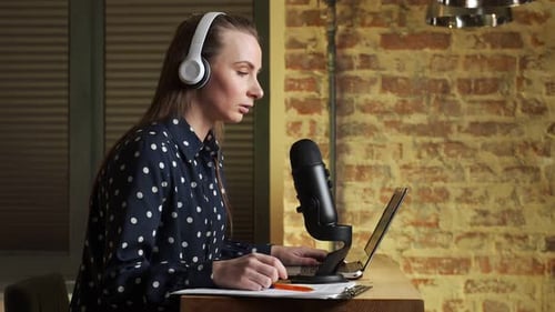 Side View Happy Woman is Recording a Podcast with Headphones and a Microphone Talking and Relaxing