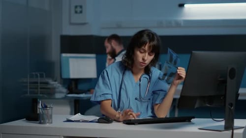 Doctor Reviews X-Ray at Night in Hospital Office