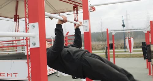 Training Motivation Athlete Man Working Out Outside on the Outdoor Gym Making Pull Ups Strong Fit