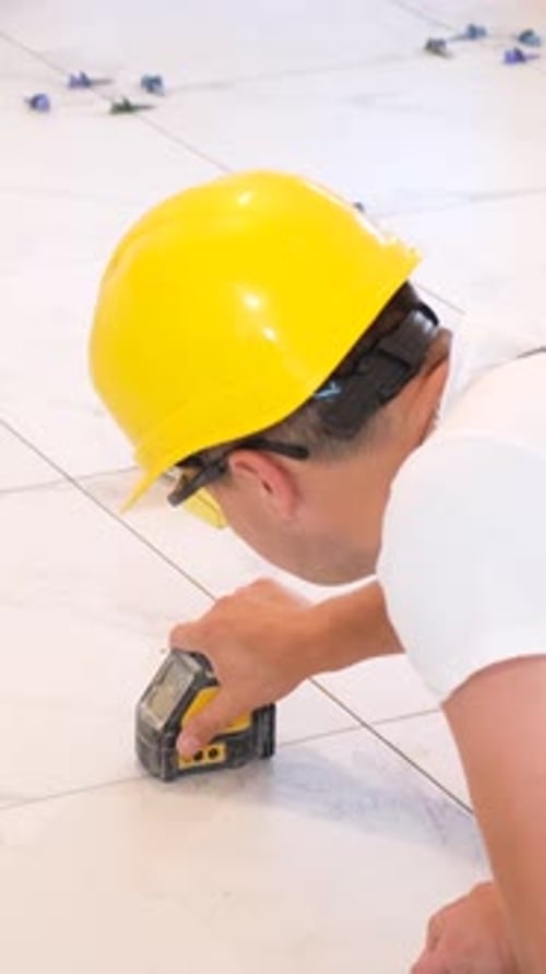 Installer Using Laser Level to Install White Tile