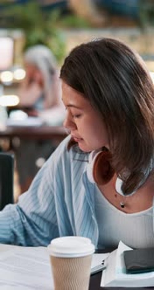Research, writing and books with Asian woman in cafeteria for studying, paperwork and college