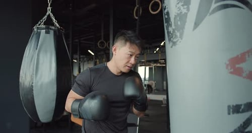 Muscular Man Boxing Punching Bag at Gym