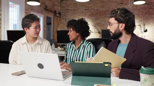 Diverse Colleagues Collaborating on Laptop in Modern Office