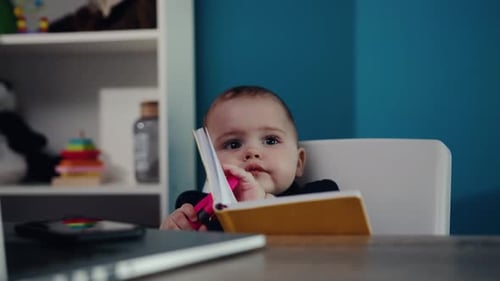 Cute Infant Holding Open Notebook Indoors