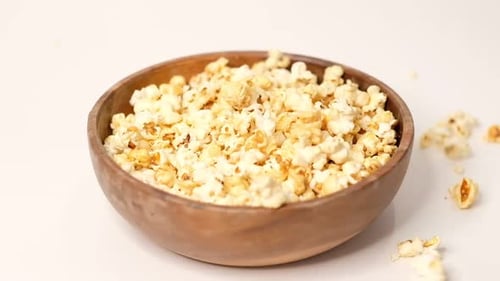 Popcorn Tossed in a Wooden Bowl on a White Background Slow Motion Video Close Up Top View