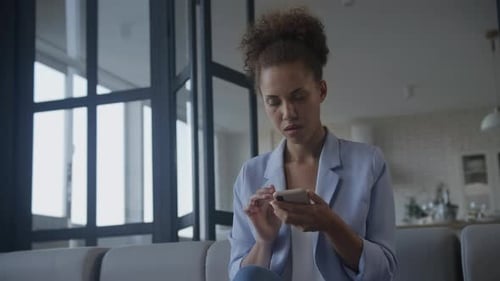Upset Woman Looks at Phone at Home