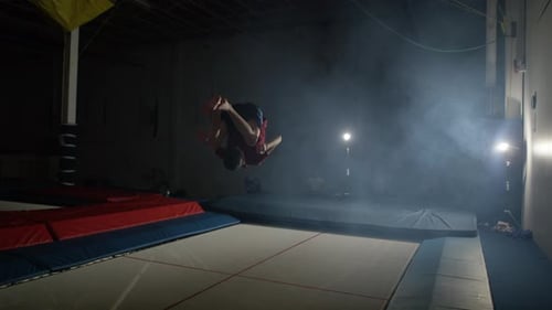 Athletic Man Flipping on Trampoline at Night