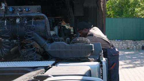 Mechanic Repairing a Semi-Truck Engine During the Day