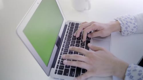 Young caucasian woman in her 30s using her laptop with a green screen to insert new content