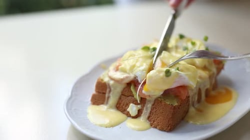 Eggs Benedict Being Cut on Toast at Breakfast