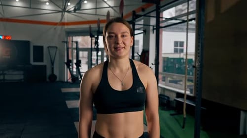 in a Sports Club Trainer in a Black Top and Leggings Stands and Poses Smiling