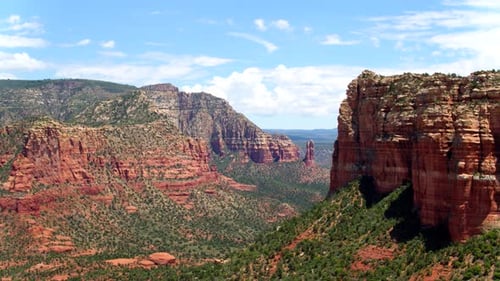 Red and green sedona cliffs dotted with shrubs viewed by drone in Arizona