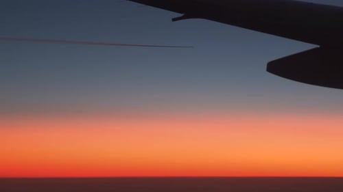 Airplane wing silhouette on background of colorful dusk.