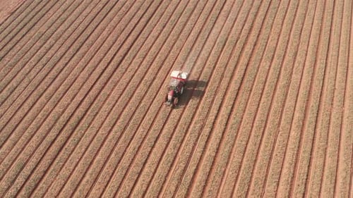 Pesticide Sprayer Tractor working on a large field, Aerial follow footage