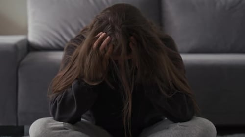 Woman Sitting on Floor Looking Distressed