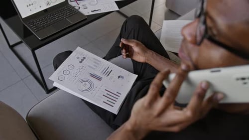 Man Discussing Data on Phone While Reviewing Charts