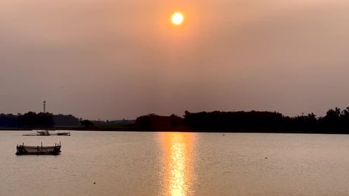 The golden sun dips below the horizon, casting a warm glow over the serene sunset lake.