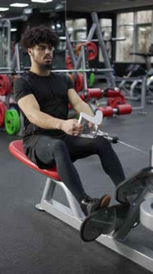 Determined Man Doing Cable Row Exercise at Gym