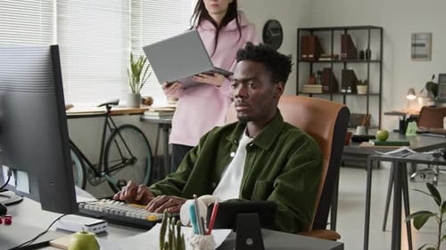 Softwareentwicklerin bittet männlichen Kollegen um Rat zum Code