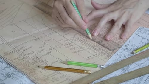 Architect using ruler and pencil to make blueprints on old paper. Engineer works with blueprints