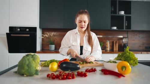 Woman Dancing While Chopping Vegetables in Kitchen