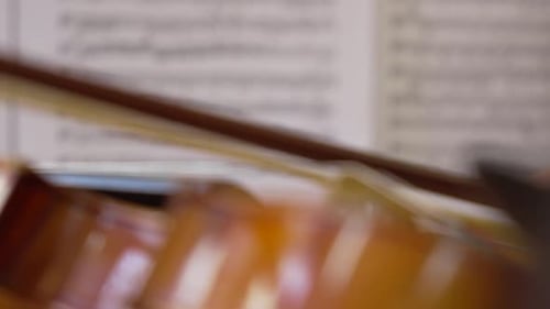 Close-Up of a Violin Focused with a Sheet of Musical Notes in the Background.